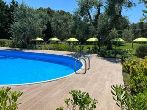 a swimming pool in a garden with umbrellas at Villa Terra Nostra in Vieste