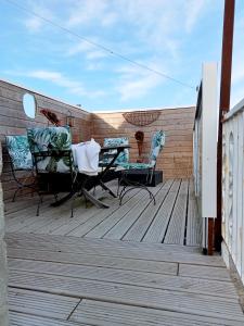 een patio met 2 stoelen en een tafel op een houten terras bij chambre k au domaine du mont scolan in Montgardon