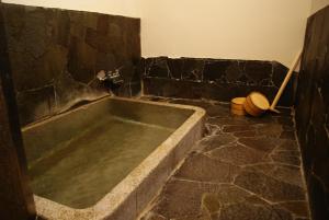 y baño con bañera grande en una pared de piedra. en Dougoya en Matsuyama