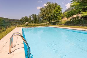 a large blue swimming pool with mountains in the background at L'Hermitage, 4 appartements avec terrasse, vue lac, parking et PISCINE, LLA Selections by Location Lac Annecy in Talloires
