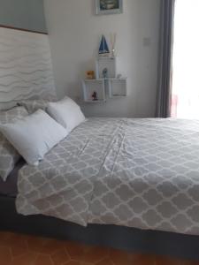 1 cama con sábanas blancas y almohadas en una habitación en Residence Le Choisy, en Grand Baie