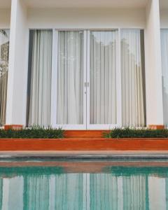 a building with white curtains next to a swimming pool at RakaAyu Kuta in Kuta