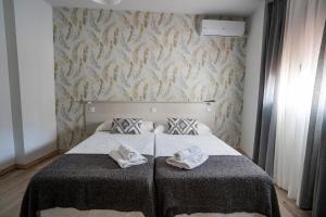 a bed with a white comforter and pillows on it at Hostal Plaza de Italia in Cáceres