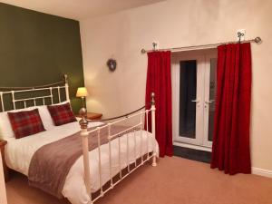 a bedroom with a bed with red curtains and a window at Underhill Holidays - Underhill Holiday Cottage in Whitby