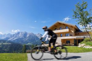 Un uomo in bicicletta davanti a una casetta di Holzhackerin - the charming Haus am Berg a Schladming