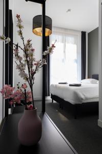 Hotel Monnickendam في مونكندام: غرفة نوم مع سرير و مزهرية مع الزهور على طاولة