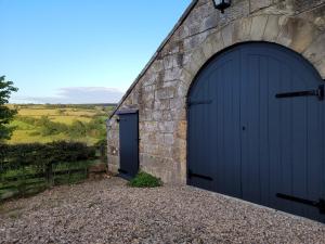 two blue garage doors on a stone building with a view at Underhill Coach House in Whitby