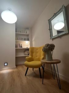a room with a yellow chair and a table with a mirror at Hostal Crisami in Solsona
