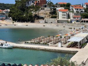 a beach with umbrellas and a boat in the water at Villas Arbia - Margita Beach hotel in Rab