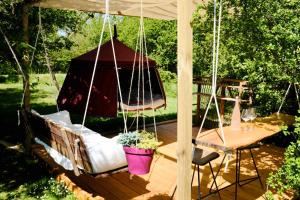 a porch swing with a gazebo and a table at Les Robinsonades in Couladère