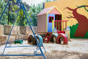 un parque infantil con un columpio y una casa de juguetes en Casa de 10 - 5b en Vejer de la Frontera