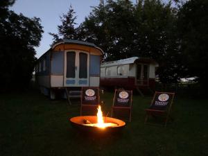 a fire in a yard with two chairs and a trailer at B&B Vennehoeve in Vremde