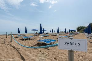 a sign on a beach with chairs and umbrellas at Pareus Beach Resort in Caorle