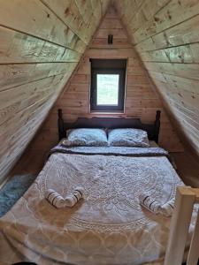 Ce lit se trouve dans une cabane en rondins dotée d'une fenêtre. dans l'établissement Etno Koliba Nikoleta, à Žabljak