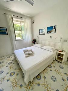 - une chambre avec un grand lit blanc et une fenêtre dans l'établissement La Bicocca di Annavì, à Ischia