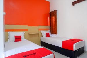 two beds in a room with red and white at RedDoorz Syariah near Alun Alun Kota Rembang in Rembang