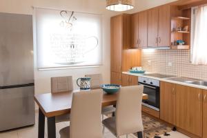 a kitchen with a wooden table and white chairs at Casa Armonia Zakynthos: 2-Floor Residence in Gaïtánion