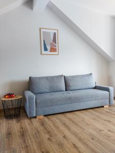 a blue couch in a living room with a wooden floor at MR HOME APARTMENTS - Limba in Kraków