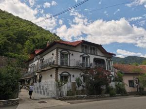 a woman walks past a white house at Casa Papava in Băile Herculane