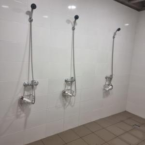 a white tiled bathroom with three shower stalls at Camp Genys in Jurbarkas +20 photos
