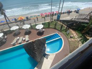 a swimming pool next to a beach with umbrellas at Flat Beira Mar- Ap 306 #ELEGANCE in Natal
