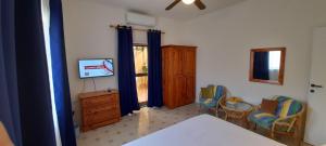 a bedroom with a bed and chairs and a window at Villa Bronja Studio airconditioned apartment Xlendi in Xlendi