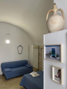 salon z niebieską kanapą i wazą na półce w obiekcie La Chicca w mieście Ostuni