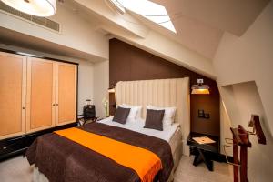 a bedroom with a large bed with an orange blanket at Astoria Hotel in Lviv