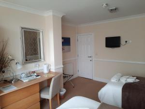a room with a bed and a desk and a television at Surrey House Hotel in Blackpool