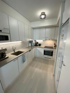 uma cozinha branca com armários brancos e um lavatório em Luxury 1-bedroom apartment with sauna and sea view em Helsinque