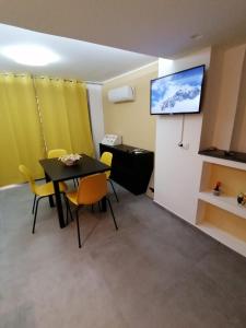 a dining room with a table and chairs and a flat screen tv at La Casa di Orlando in Catania