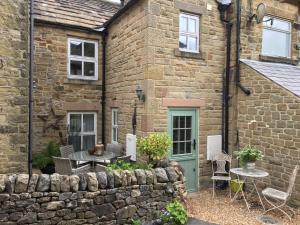a stone house with a table and chairs in front of it at Carr’s cottage Eyam Peak District, in Eyam