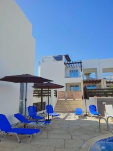 eine Gruppe blauer Stühle und Sonnenschirme auf einer Terrasse in der Unterkunft 3 Bedroom Seaview Villa direct in Coral Bay with Pool in Coral Bay