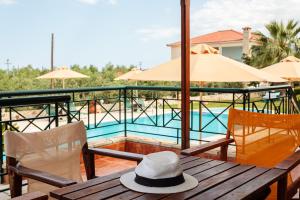 un sombrero sentado en una mesa de madera junto a una piscina en Astros Endless Sunsets - Dukes Poolside Homes, en Paralio Astros