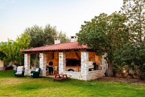 a stone house with a fireplace in a yard at Dukes Poolside Houses in Paralio Astros