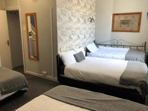two beds in a hotel room with a mirror at Ultimate Family Guest House in Blackpool