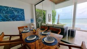 a dining room with a wooden table and a view of the ocean at Diamond Villa in Laem Sor
