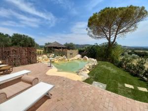 a backyard with a small pool with a rock retaining wall at Agriturismo La Fontanella & Glamping in Suvereto