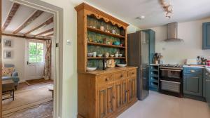 a kitchen with a wooden cabinet and a stove at Alba Cottage, Wilcot, Pewsey in Wilcot