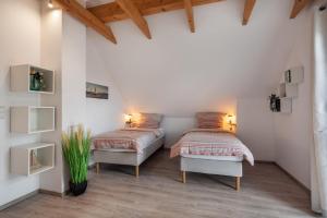 two beds in a room with white walls and wood floors at Seeblick Warin in Warin