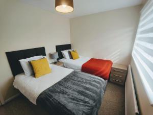 two beds in a small room with yellow and orange pillows at Piping House 4bedroom in Otterbourne