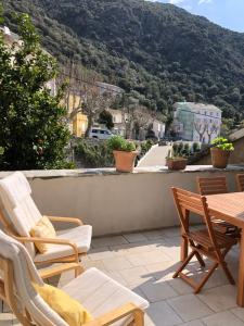 een patio met stoelen en een tafel en een berg bij Chez Jean Nonza in Nonza