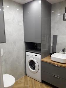 a bathroom with a washing machine and a sink at Apartament Wiżajny in Wiżajny