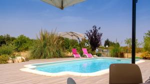 a swimming pool with two pink chairs and an umbrella at Dimore Tarantini in Polignano a Mare