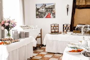a dining room with white tables and plates of food at Hotel Gut Landscheid in Burscheid