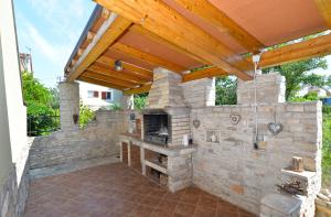 eine Außenküche mit einer Steinmauer und einem Holzdach in der Unterkunft Apartment Damira 1017 in Fažana
