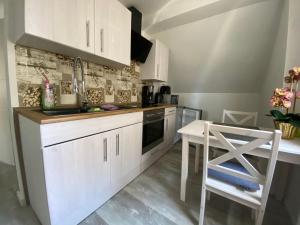 a kitchen with white cabinets and a sink and a table at Pension Eckert in Zwenkau