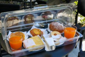 a plastic container filled with different types of pastries and orange juice at Hotel Three in Vlorë