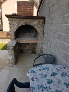 a stone fireplace with a table in front of it at Apartman DIVA in Otočac