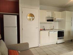 uma pequena cozinha com armários brancos e um lavatório em Superbe appartement avec piscine sauna et petite vue mer em Plougonvelin